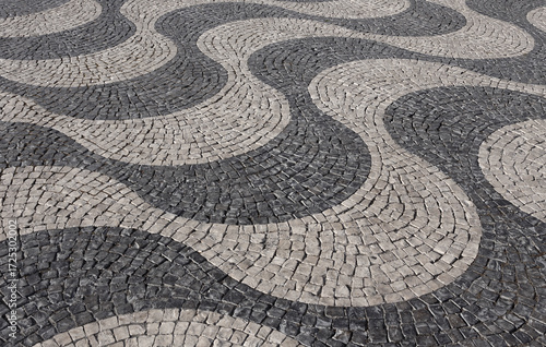 Lisbon, Portugal. Typical Portuguese black and white stone mosaic calcada pavement - found throughout Portugal. Also found in Brazil and other previous Portuguese colonies. Wavy pattern. 