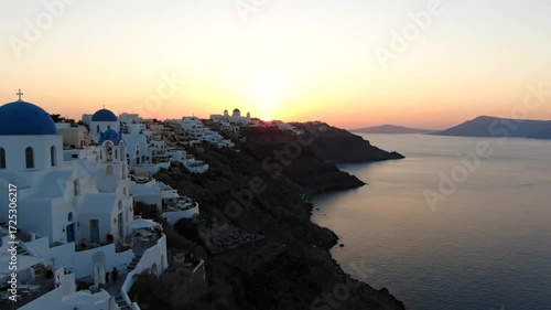 Picturesque view of santorini village at sunset, showcasing the iconic white buildings, blue domes, and stunning coastal scenery, creating a romantic and idyllic travel destination