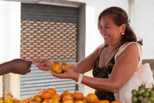 Woman buying oranges smiling at fruit market