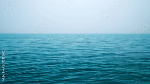 Tranquil expanse of still water, showcasing the deep blue hues of the ocean's surface, with a serene sky.