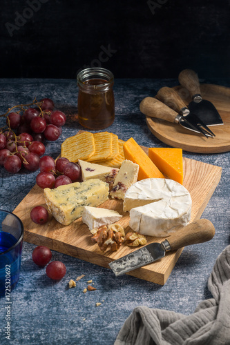 Cheese board, different types of cheese on a board, served with grapes and dried fruits.