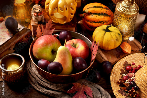 Autumn still life with a bowl of seasonal fruits, pumpkins and decors on rustic table