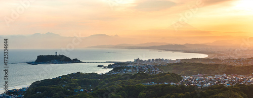 Aerial view of Enoshima Island and Mount Fuji shrouded in the distance under a golden sky, Kamakura, Kanagawa, Japan.
