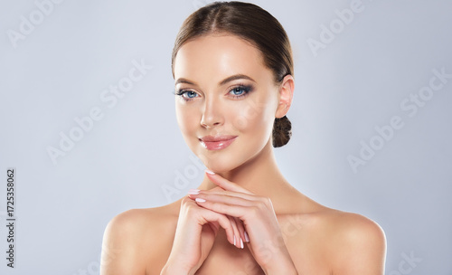 Beautiful Young Woman with Clean Fresh Skin touch own face . Facial treatment . Cosmetology , beauty and spa 