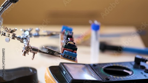 Close-up of hands soldering a printed circuit board with a soldering iron in a workshop. Concept of electronics repair, technology, DIY, and microchip maintenance.