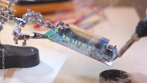 Close-up of hands soldering a printed circuit board with a soldering iron in a workshop. Concept of electronics repair, technology, DIY, and microchip maintenance.