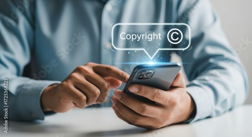 A man using a smartphone with a copyright symbol on the screen, protecting intellectual property and preventing infringement of rights