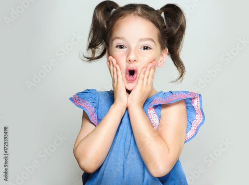 The child is a beautiful girl with wide eyes, look away in surprise. Baby in a knitted sweatshirt . Children's products , clothing and accessories . Expressive facial emotions