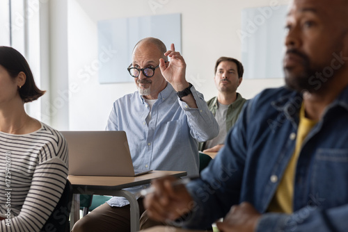 Engaged adult student raising his hand in class