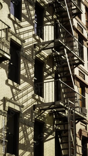 Wallpaper Mural Fire escapes intertwine along the facade of a vintage building with modern skyscrapers looming in the background. The golden hour casts dramatic shadows, evoking a sense of history and urban vibrance. Torontodigital.ca