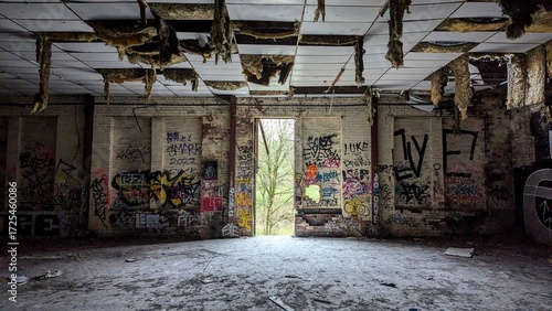 Abandoned industrial factory warehouse building interior. Dark empty Rishton Paper Mill. Broken ceiling tiles, dusty floor, graffiti walls. Daylight though open doorway, escape urban decay to nature.