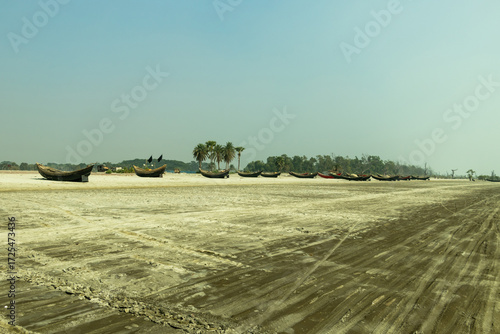 Fotografie A calm coastline with flat sandy beaches, a row of wooden sampans
