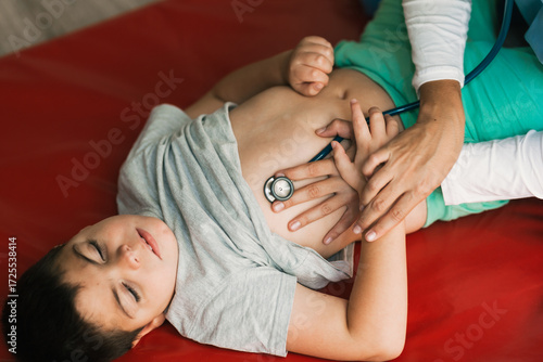 Doctor examining child's lungs with stethoscope during respiratory physiotherapy session
