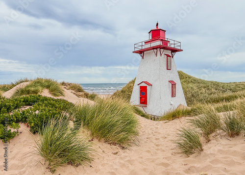 Diminutive St. Peter’s Harbour Lighthouse, sand dunes,  and the Atlantic Ocean on the eastern side of Prince Edward Island, Canada