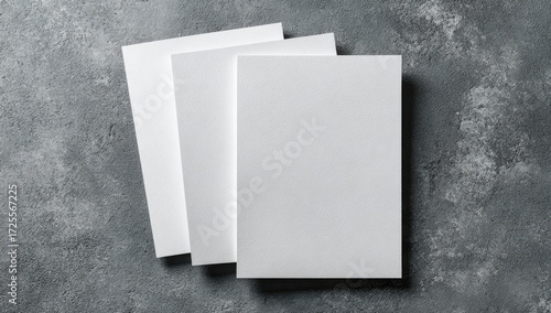 Three blank white brochures stacked on a textured gray surface