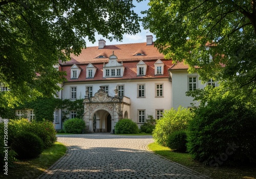 Wallpaper Mural A grand, historic manor house with a redtiled roof, surrounded by lush green trees and bushes, with a cobblestone driveway leading to the entrance Torontodigital.ca