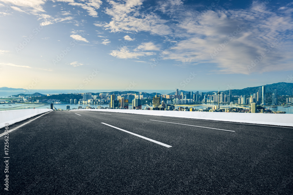 Fototapeta premium Empty asphalt road with a modern city skyline and sea view.