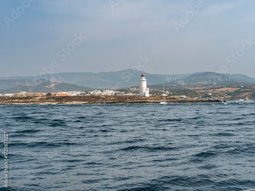 Tarifa island, lighthouse and Spanish mainland as seen from the straits of Gibraltar. When sailing eastward trough the strait, The Tarifa Island is one of the first things you encounter