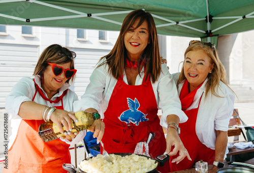 Three friends enjoying outdoor cooking together at a street event