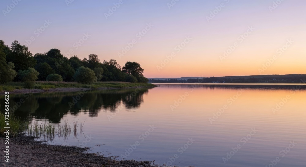 Naklejka premium Calm lake at sunset reflecting trees