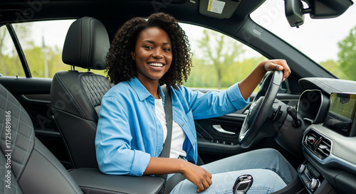 Radiant Black woman beaming with joy while driving her modern car on a scenic road, embodying freedom and independence on a bright sunny day