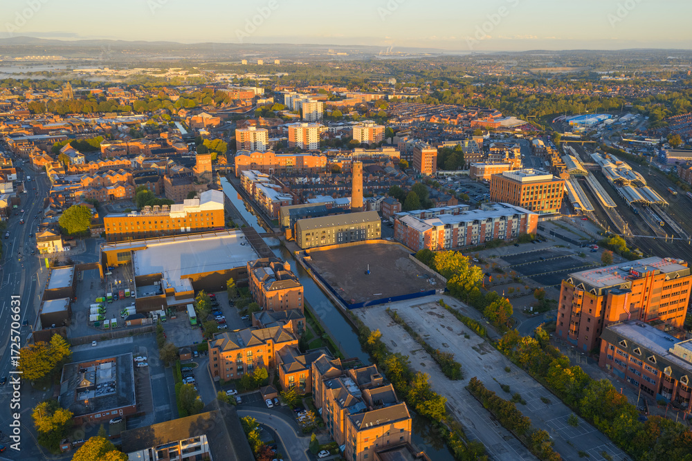 Obraz premium Sunlit aerial view of Chester Railway Station with canal, warehouses, and historic chimney.