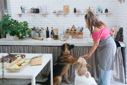 Canvas Print woman baking pears with ricotta and walnuts, and playing with dogs