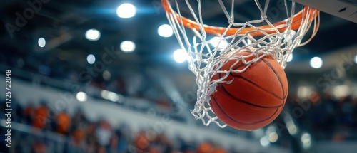 The basketball soaring through the net in an exciting indoor sports arena.