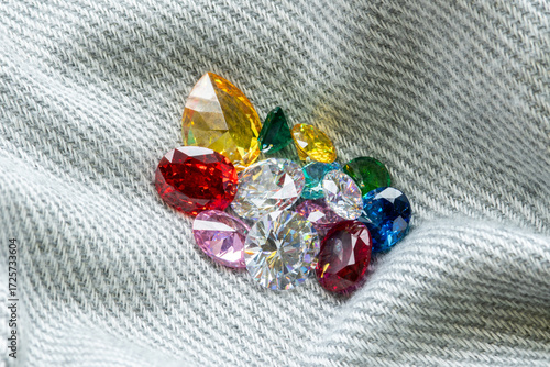 Colorful gemstones in various shapes and cuts placed on denim fabric background, representing luxury, fashion accessories, creativity, and jewelry design inspiration.
