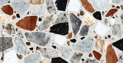 A detailed close-up captures the intricate texture of terrazzo, showcasing a blend of diverse stone fragments in varying sizes, shapes, and colors, embedded in a light-toned matrix