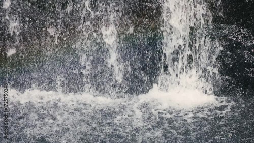Beautiful waterfall drops splashing on water surface in slow motion calm nature background, perfect abstract video for relaxation, spa, travel, advertising and documentary projects. 120 fps video.