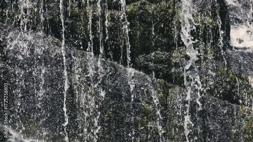 Beautiful waterfall streams flowing down the cliff in slow motion against the background of calm nature, an ideal abstract video for relaxation, spa, travel, advertising projects. Video at 120 fps.