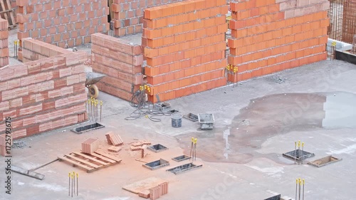 Multistory Building Construction Site with Red Hollow Brick Cinder Block Walls Protruding Reinforcement Rebar Rods with No Workers Around