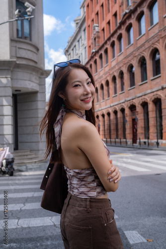 A woman wearing a brown dress and sunglasses is standing on a street. travel concept.