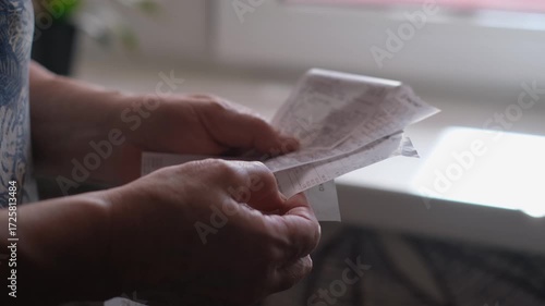 An elderly woman holding receipts from a store, close-up