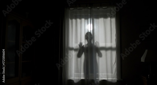 Silhouette of a person standing behind a closed curtain, illuminated by an unknown light source, creating a sense of mystery, suspense, and a hidden presence.