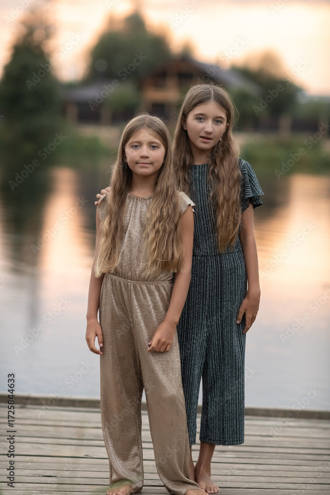 Fototapeta premium Portrait of two beautiful dressed children sisters outdoors.