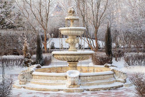 A fountain in a winter landscape park. A place of rest in a big city. Climate, weather.