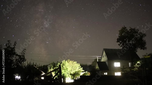 Milky way galaxy moving across starry night sky above house