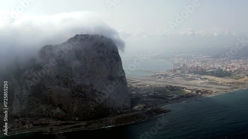 The rock of gibraltar is shrouded in mist and cloud on a hazy day