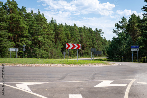 Tableau sur toile Bright sunny day at a rural roundabout surrounded by green trees in a tranquil l