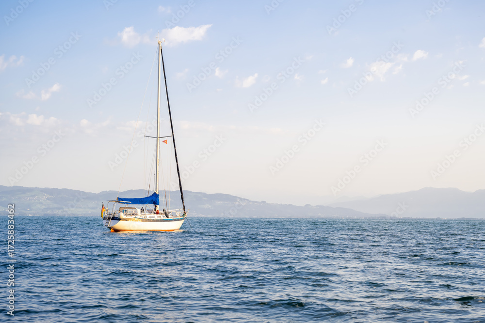 Naklejka premium a sailboat illuminated by the sun against the backdrop of a mountainous coastline
