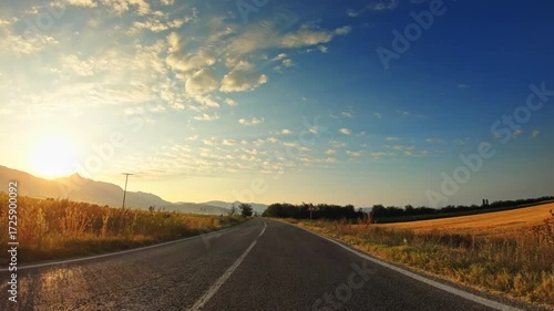 Beautiful sunset, golden valley fields, clouds, POV driver perspective