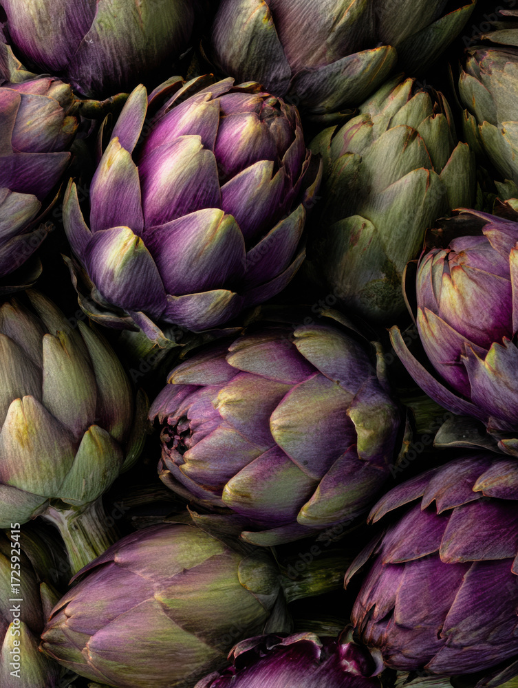 Obraz premium Fresh artichokes in shades of purple and green stacked closely on a table ready for cooking or market sale in a vibrant kitchen