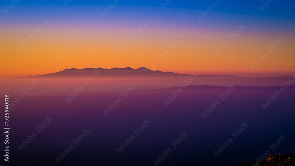 Fototapeta premium Dramatic mountain range silhouette at sunset with vibrant colors and hazy atmosphere