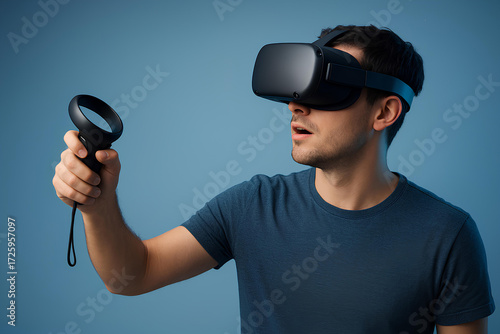Young man using VR headset and controller, exploring immersive virtual reality technology with focus and excitement on blue background