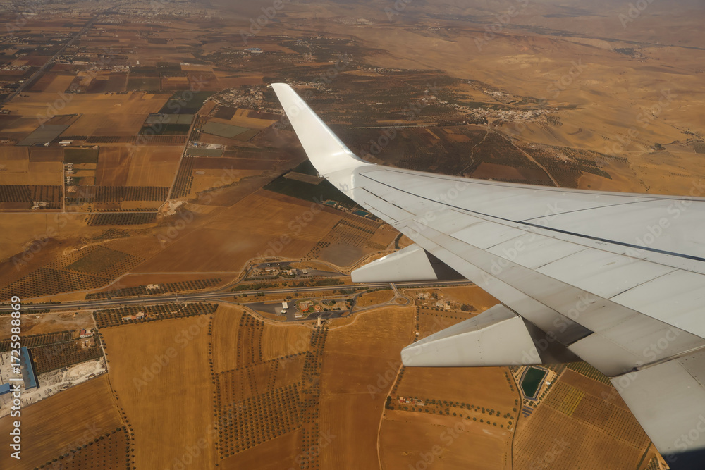 Obraz premium Aerial view of rural landscape and airplane wing in flight over Morocco.