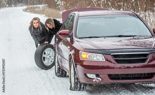 Female using changing wheel. Womans changing the punctured tyre on his car in winter. Girl replacing tyres. Fault car in the winter
