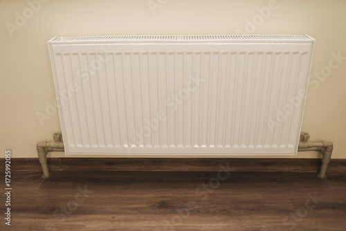 Wallpaper Mural 
White metal radiator mounted on the wall of a modern home interior. Heating equipment provides warm temperature and comfort during cold winter days. Torontodigital.ca