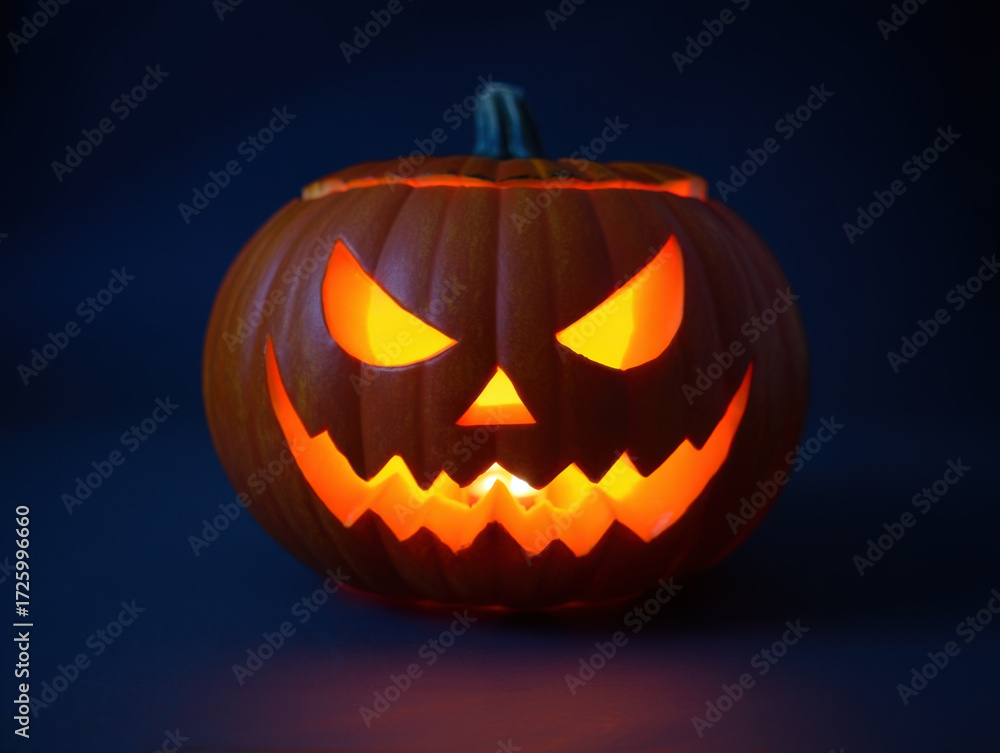 Fototapeta premium Carved halloween pumpkin glowing in dark setting